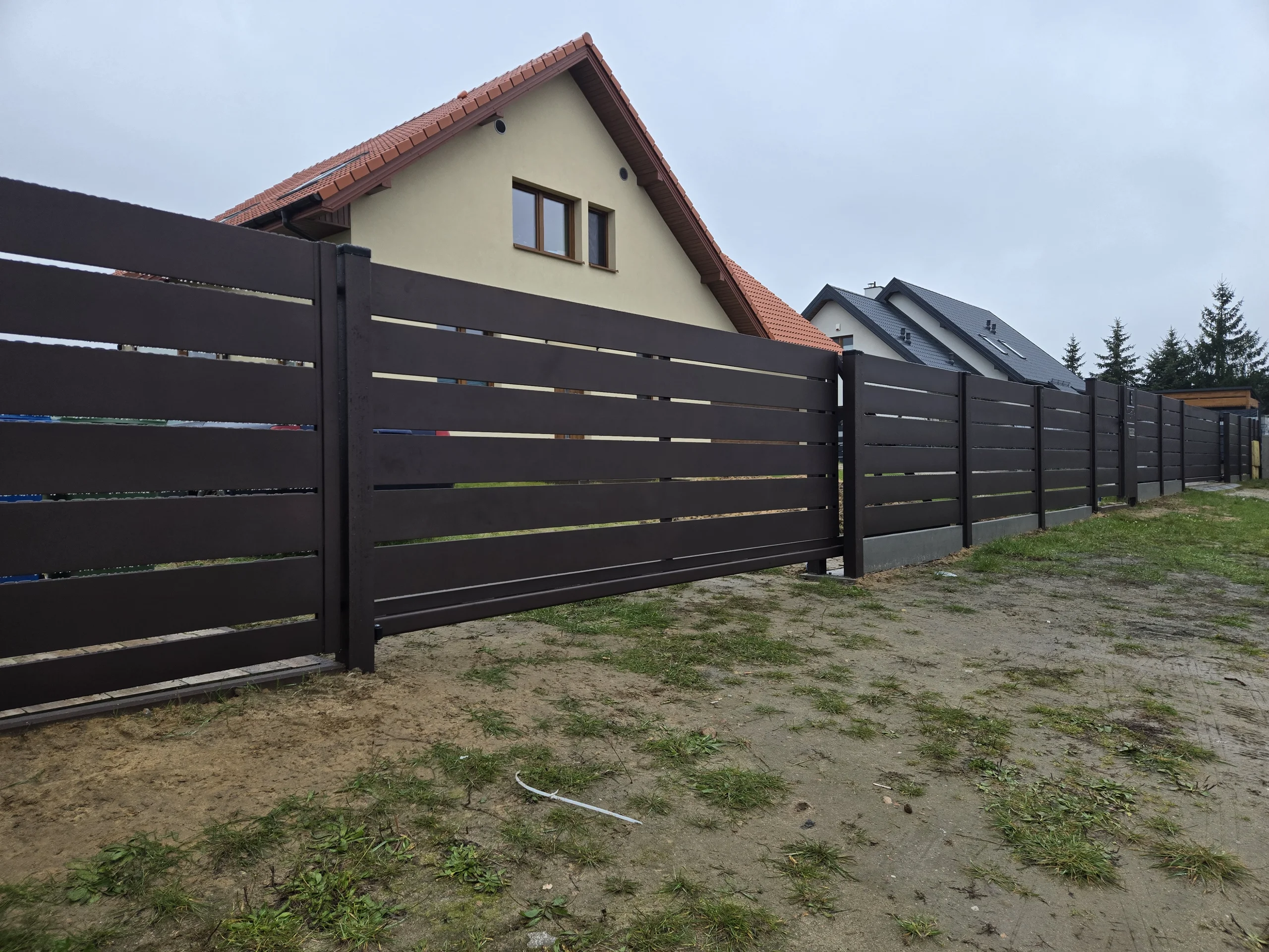 Ogrodzenie żaluzjowe z poziomych brązowych paneli przed nowoczesnym domem